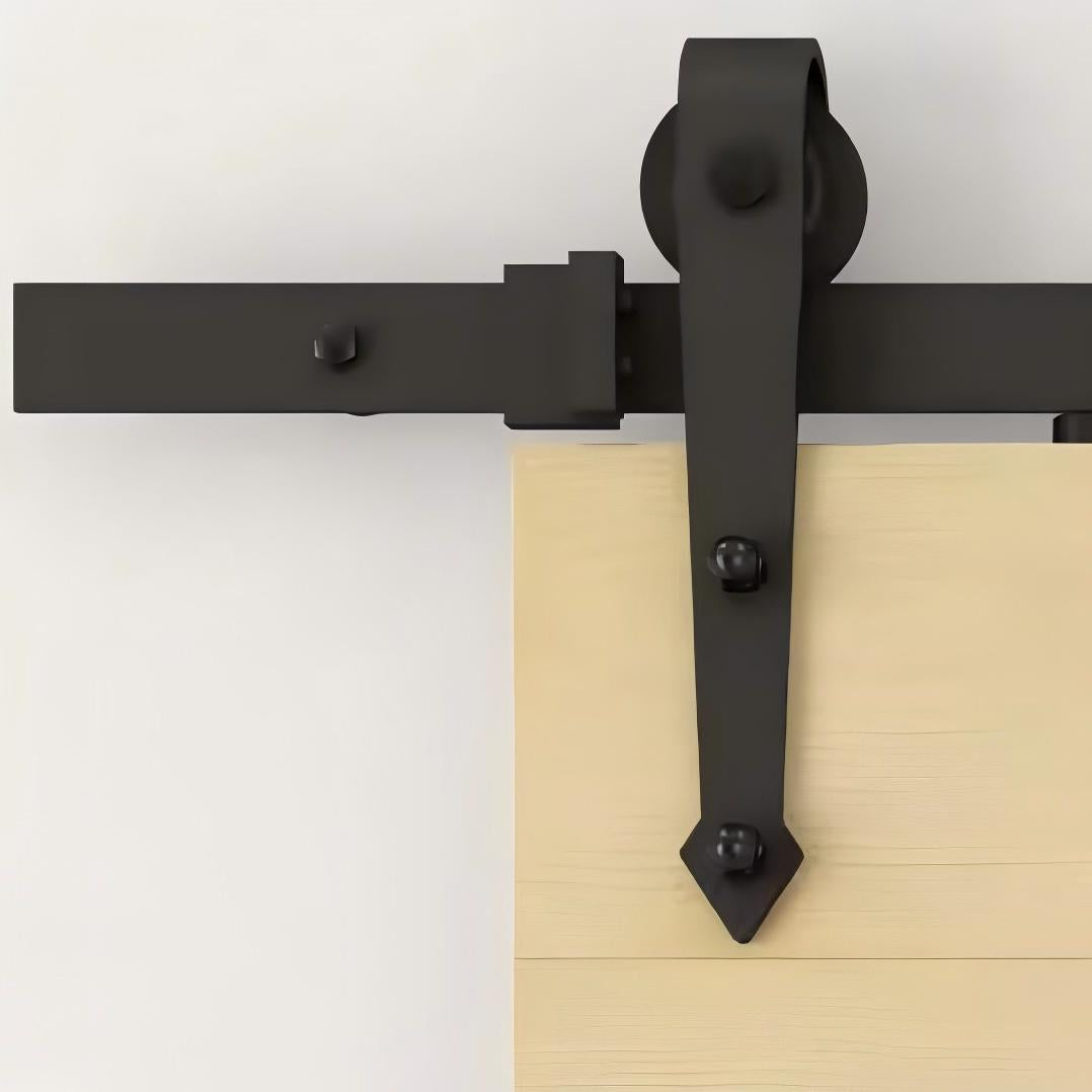 Black carbon steel sliding barn door hardware kit with arrow design on a wooden door, featuring a modern aesthetic.
